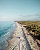 Una playa con un vehículo en la arena.