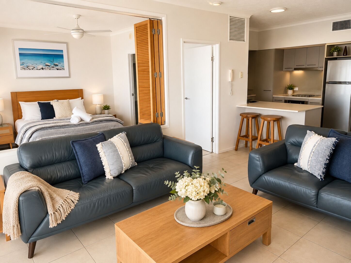 A modern living room with a sofa, coffee table, and a bed with a view.
