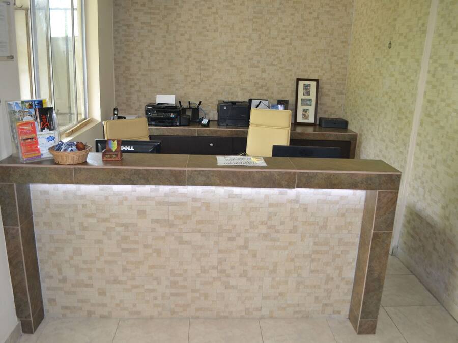 A reception desk with a tiled backsplash, a window, and various office supplies.