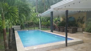 Una piscina rectangular con borde de azulejos, rodeada de un patio también con pavimento de azulejos.