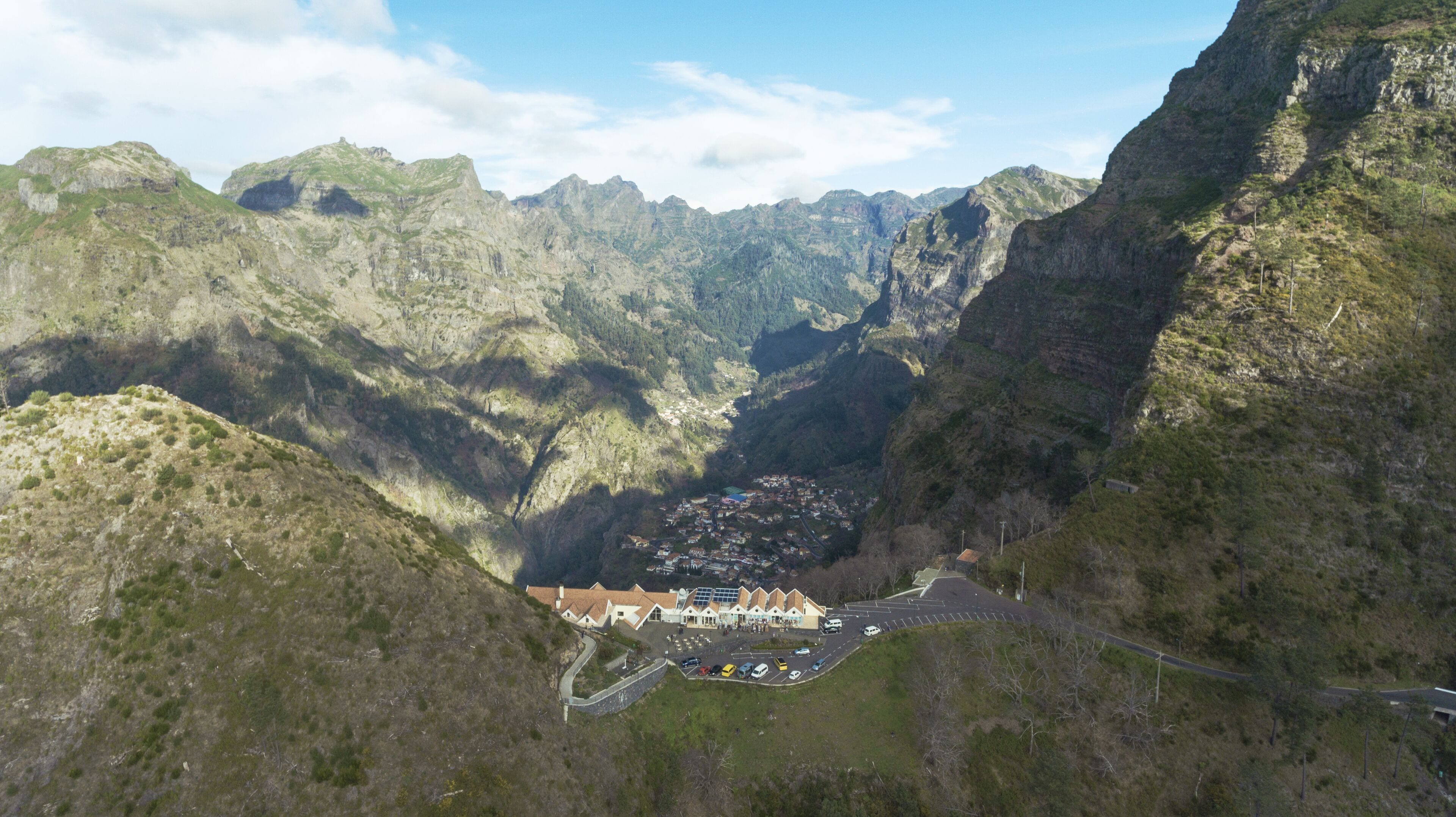 Eine gebirgige Landschaft mit einem Tal und einer kleinen Stadt mit Gebäuden und einem Parkplatz.