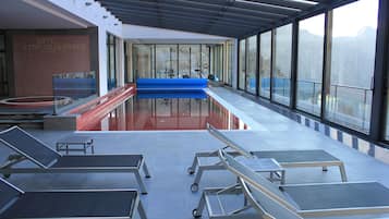 Un área de piscina interior moderna con tumbonas y equipo de ejercicio.