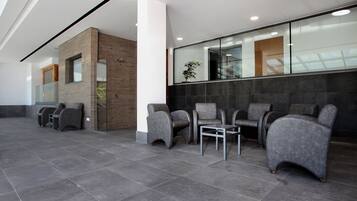 A modern waiting area with grey upholstered chairs, a small table, and a glass partition.