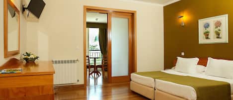 A bedroom with a bed, a dresser, a mirror, and a wall-mounted light fixture.