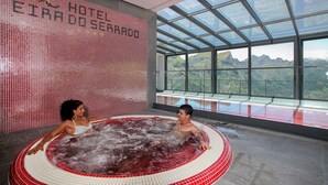 A hot tub with a tiled wall and a view of mountains through large windows. - Eira do Serrado Hotel & SPA (Camara de Lobos)