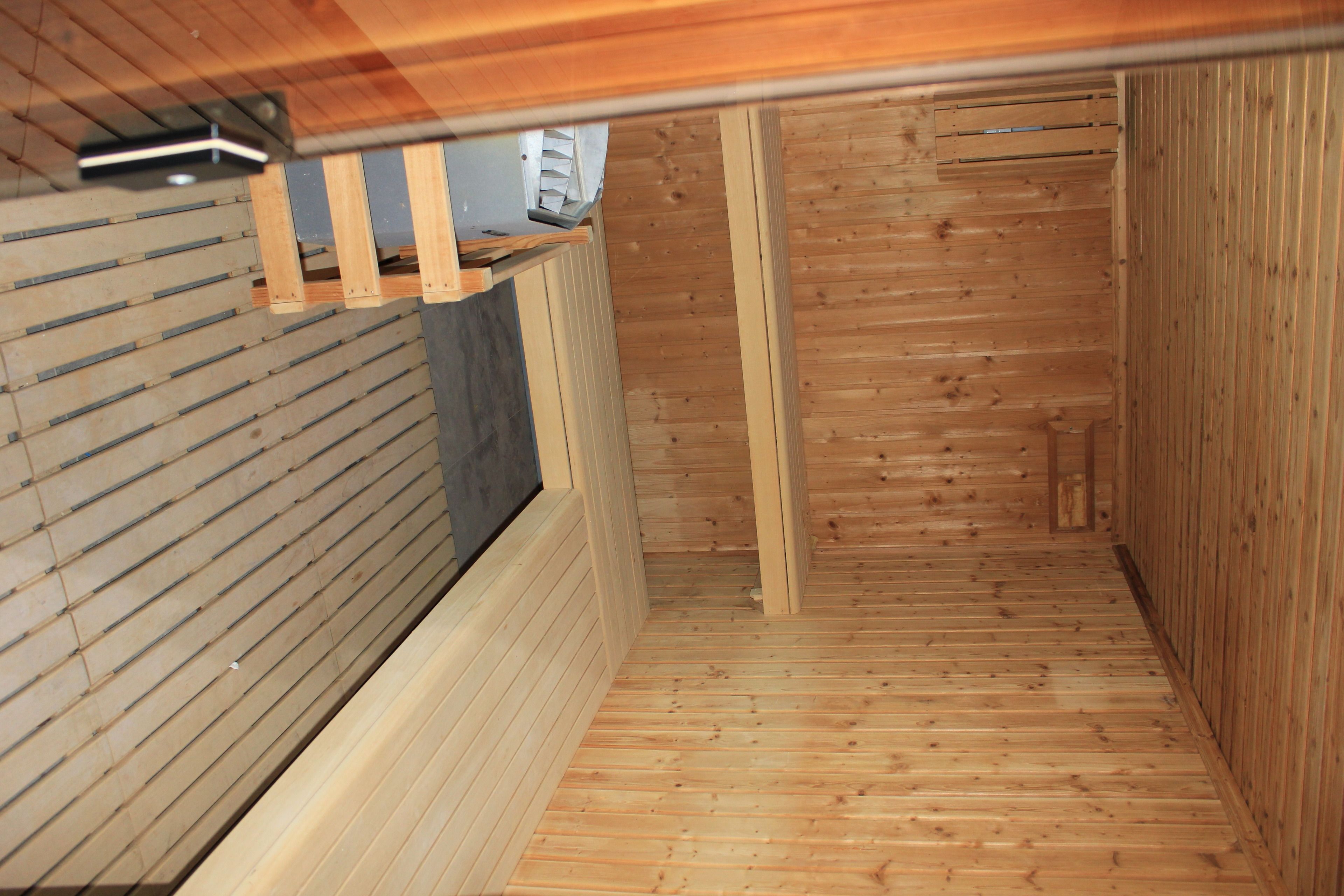 A narrow wooden corridor with a sloped ceiling and a window on the left.