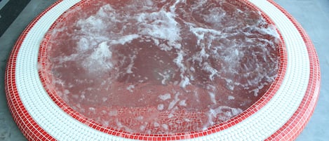 A circular hot tub with a red and white tiled border.