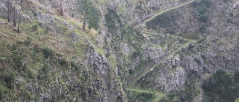 A rugged mountainous landscape with terraced fields and sparse vegetation.