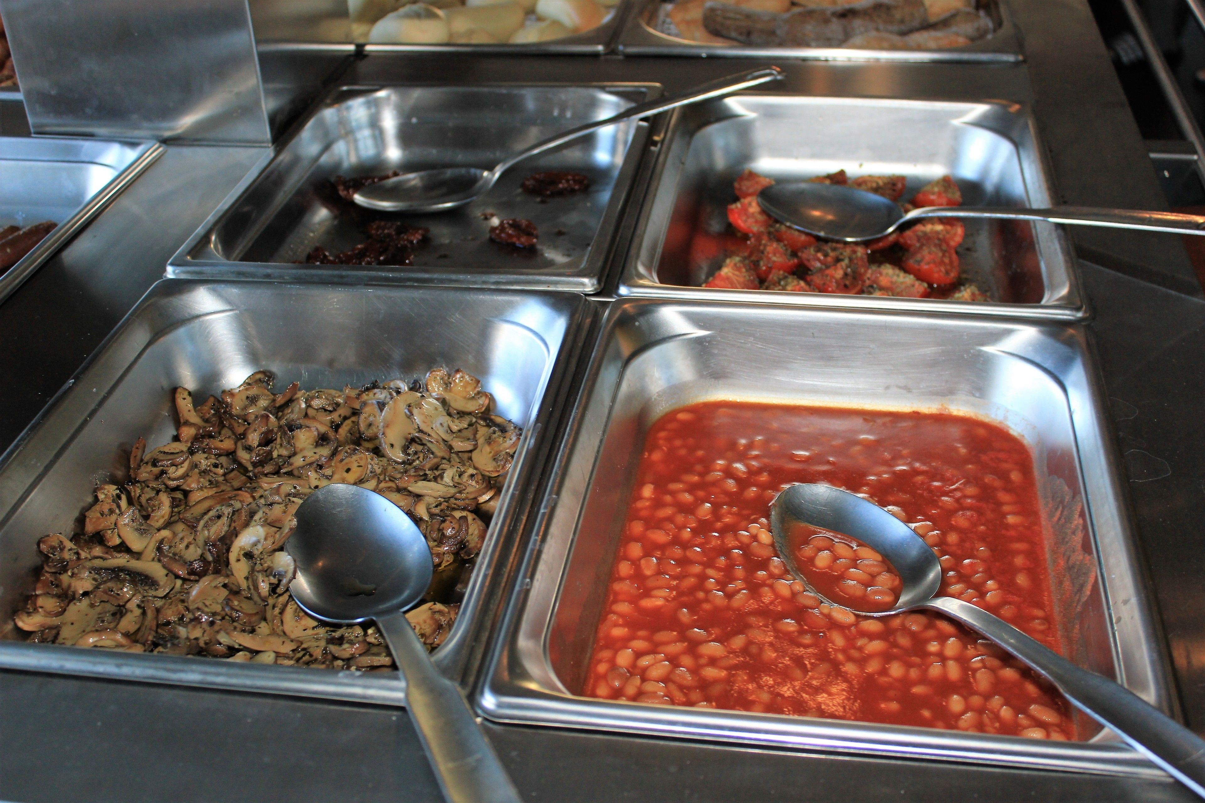 A buffet with various food options including beans and mushrooms.