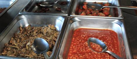 A buffet with various food options including beans and mushrooms.