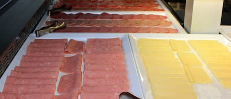 A display of various meats and cheeses in a refrigerated case.