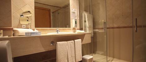 Ein Badezimmer mit Duschkabine aus Glas, Waschbecken mit Spiegel und Toilette.