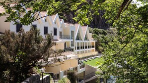 A multi-story hotel with a white facade, terracotta roof tiles, and a pool area. - Eira do Serrado Hotel & SPA (Camara de Lobos)