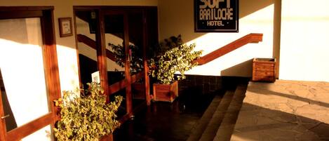 A hotel entrance with a staircase, wooden handrails, and potted plants.
