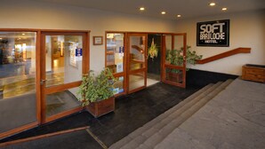 Entrada de un hotel con puertas de vidrio, una escalera y un letrero que dice Softh Bariloche Hotel.