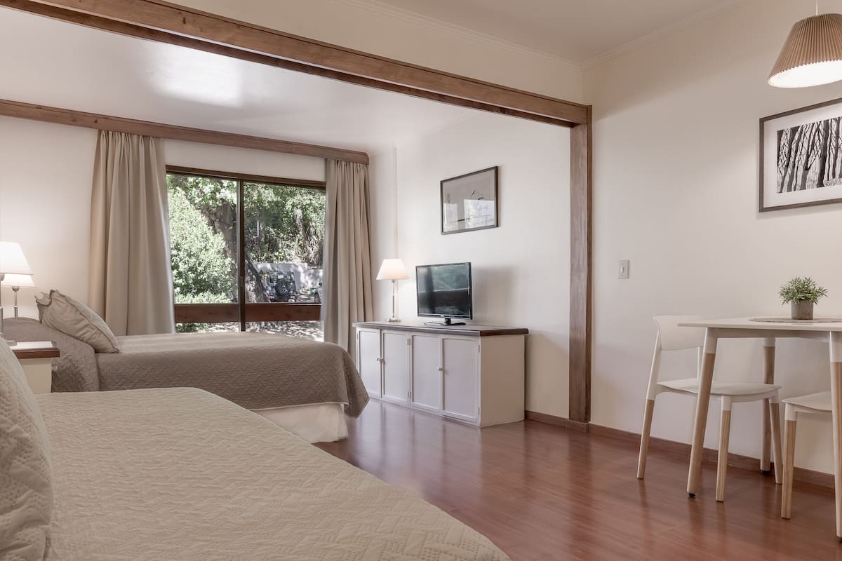 A hotel room with two beds, a TV, a desk, and a chair.