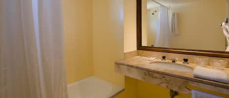 Un baño con una bañera, un lavabo de dos grifos, un espejo y un perchero para toallas.