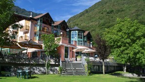 Un hotel con diversi piani, area salotto esterna e vista su un paesaggio montuoso.