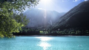 Un lago tranquillo con montagne sullo sfondo, cieli sereni e alcune persone che si godono l'acqua.