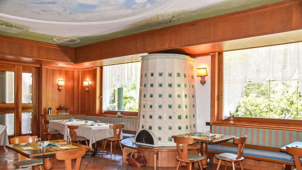 Un restaurante con paneles de madera, mesas redondas y una columna decorativa central.