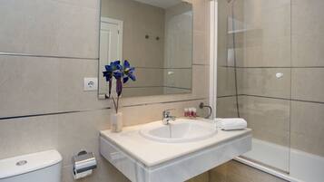 A modern bathroom with a large mirror, a sink, a toilet, and a glass-enclosed shower.