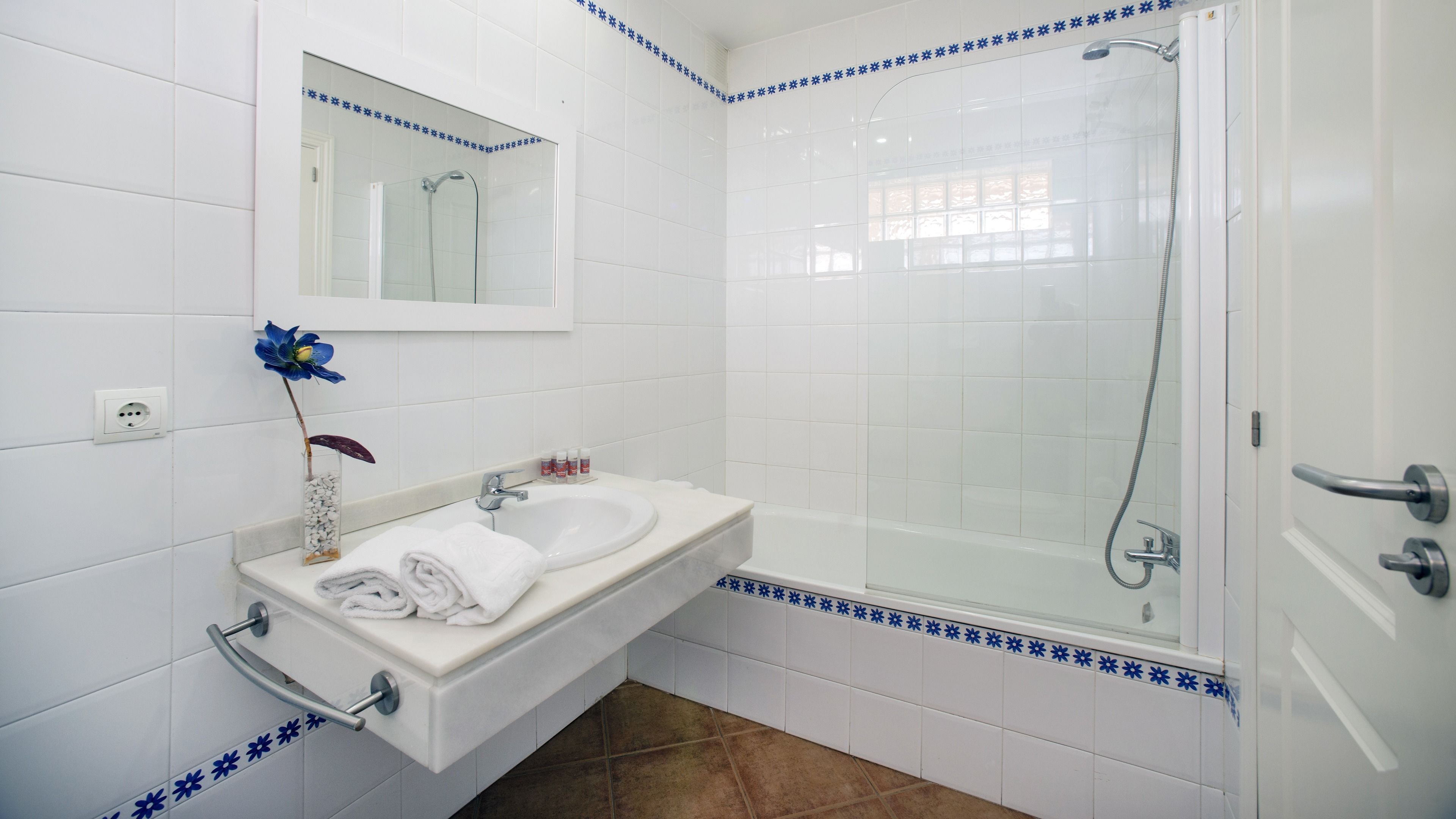 Un baño con lavamanos blanco, espejo y ducha.