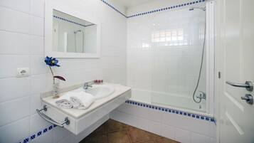 Un baño con lavamanos blanco, espejo y ducha.