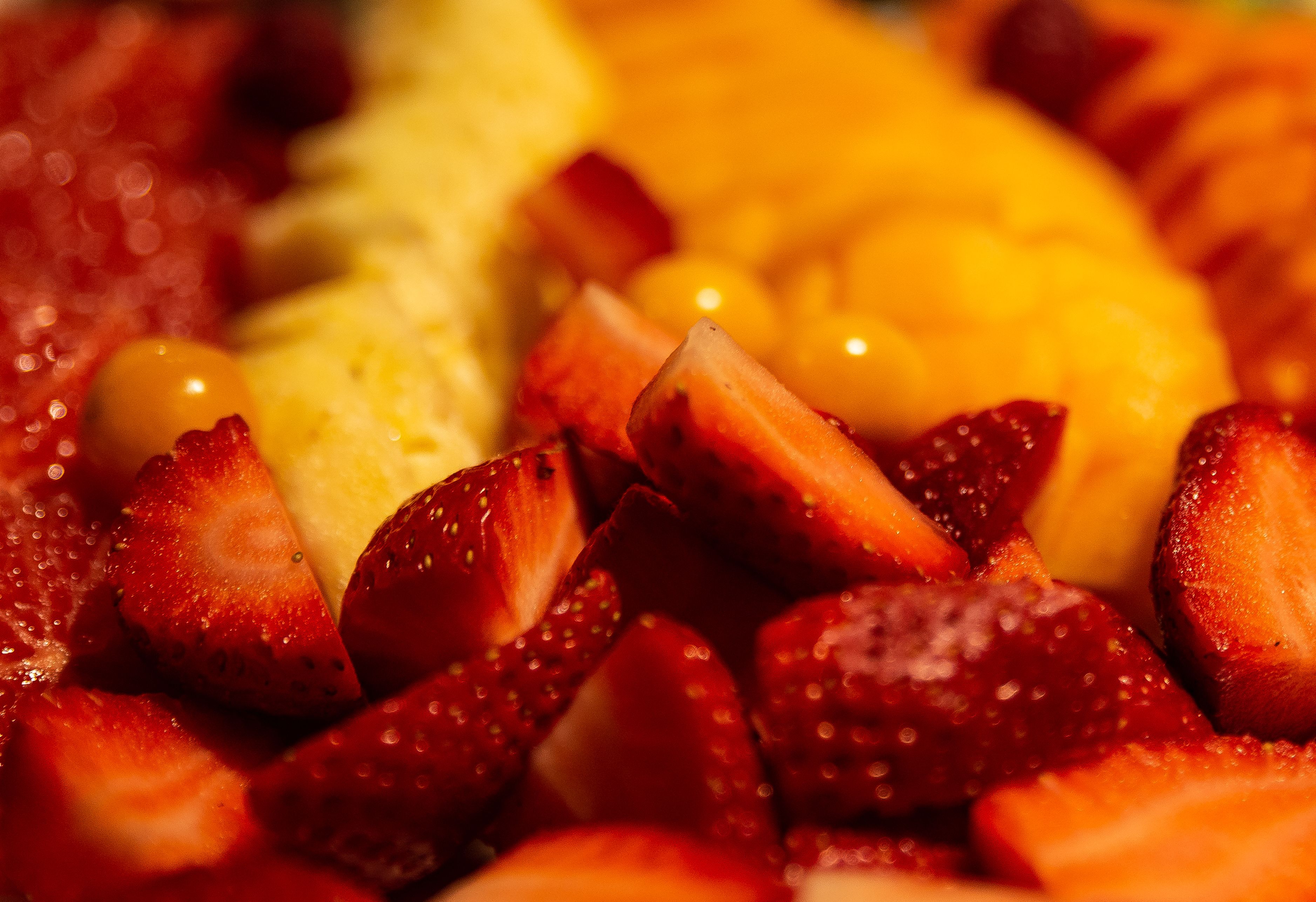 A close-up of a fruit platter with strawberries and a yellow fruit, possibly mango.
