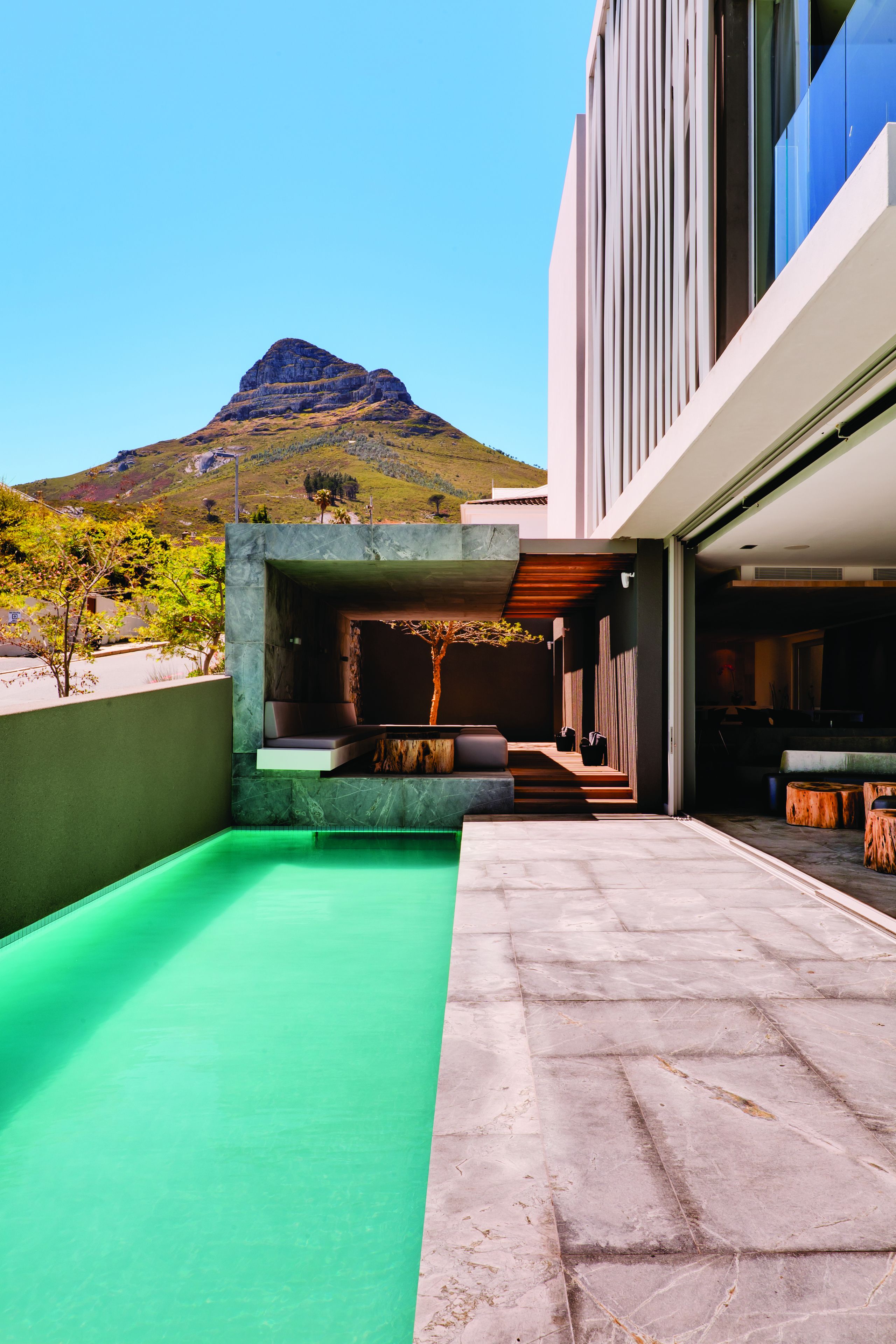 A modern outdoor patio with a green floor, seating area, and a view of a mountain.