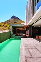 Un patio moderno al aire libre con suelo verde, zona de estar y vista a la montaña.