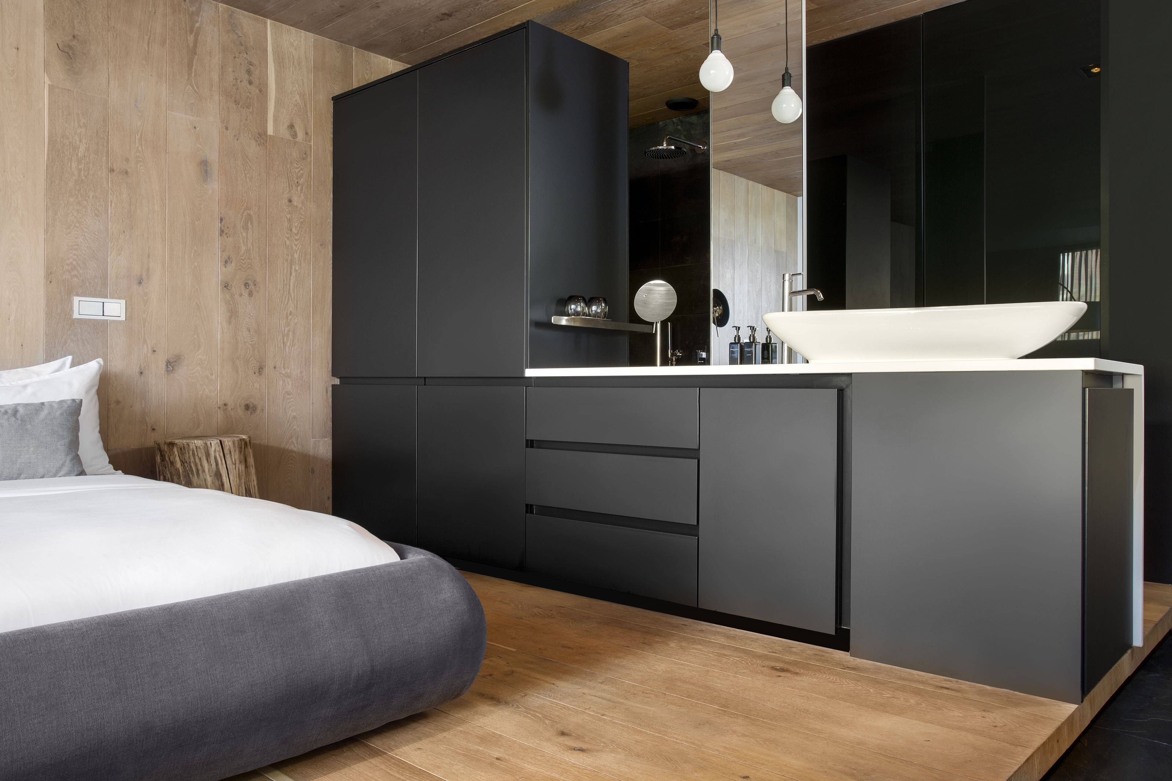 Un dormitorio moderno con una cama grande, suelo de madera y un armario negro.