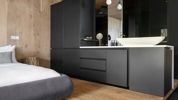 A modern bedroom with a large bed, a wooden floor, and a black wardrobe.