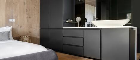 Un dormitorio moderno con una cama grande, suelo de madera y un armario negro.
