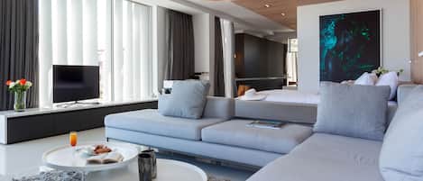 A modern living room with a grey sofa, a white coffee table, and a flat-screen TV.