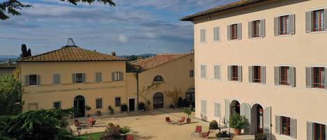 A courtyard with outdoor seating and a building with multiple windows and doors.