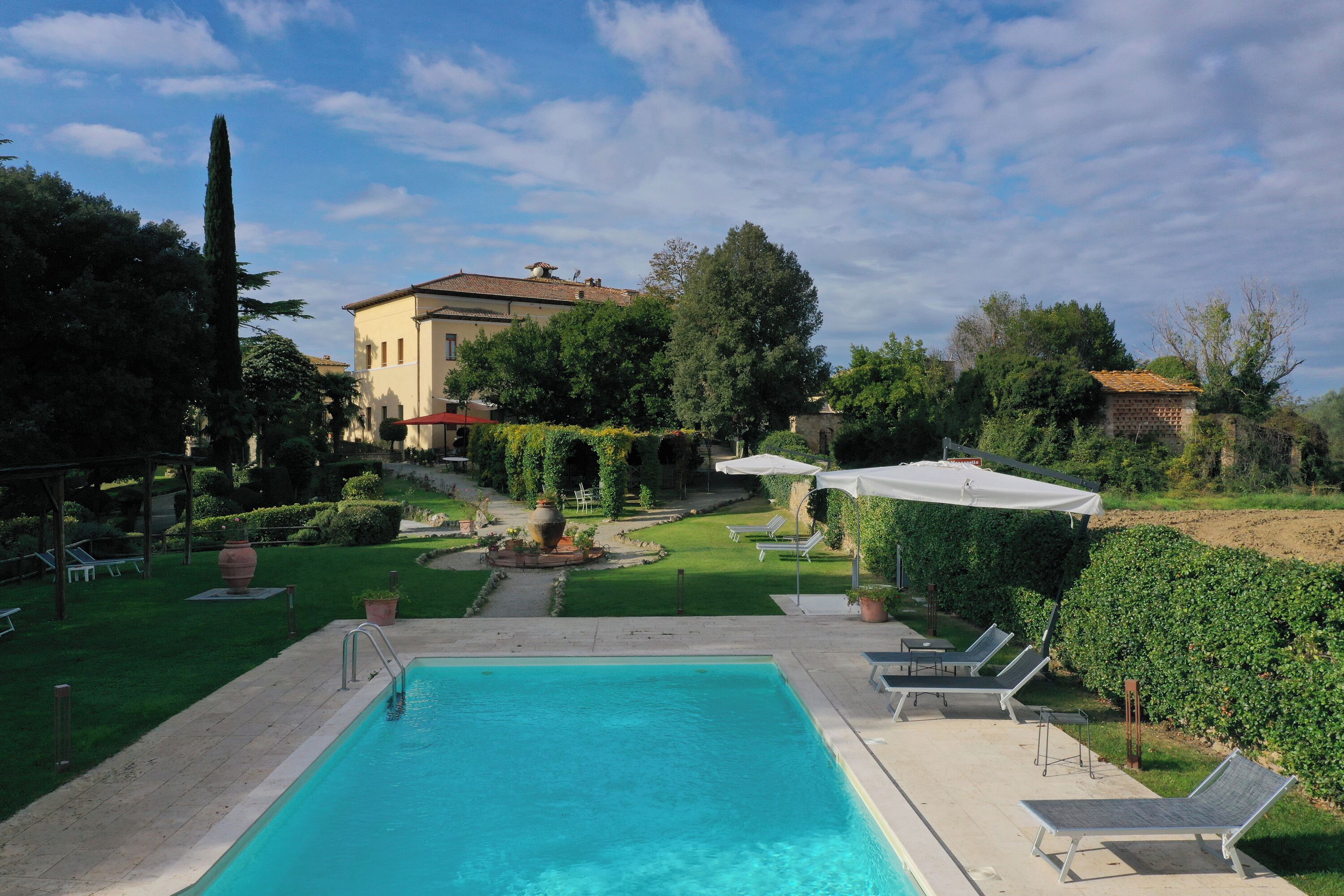 A swimming pool with lounge chairs and a garden area.