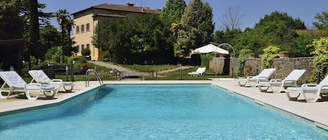 Una piscina cristalina con sillas de descanso y un edificio al fondo.