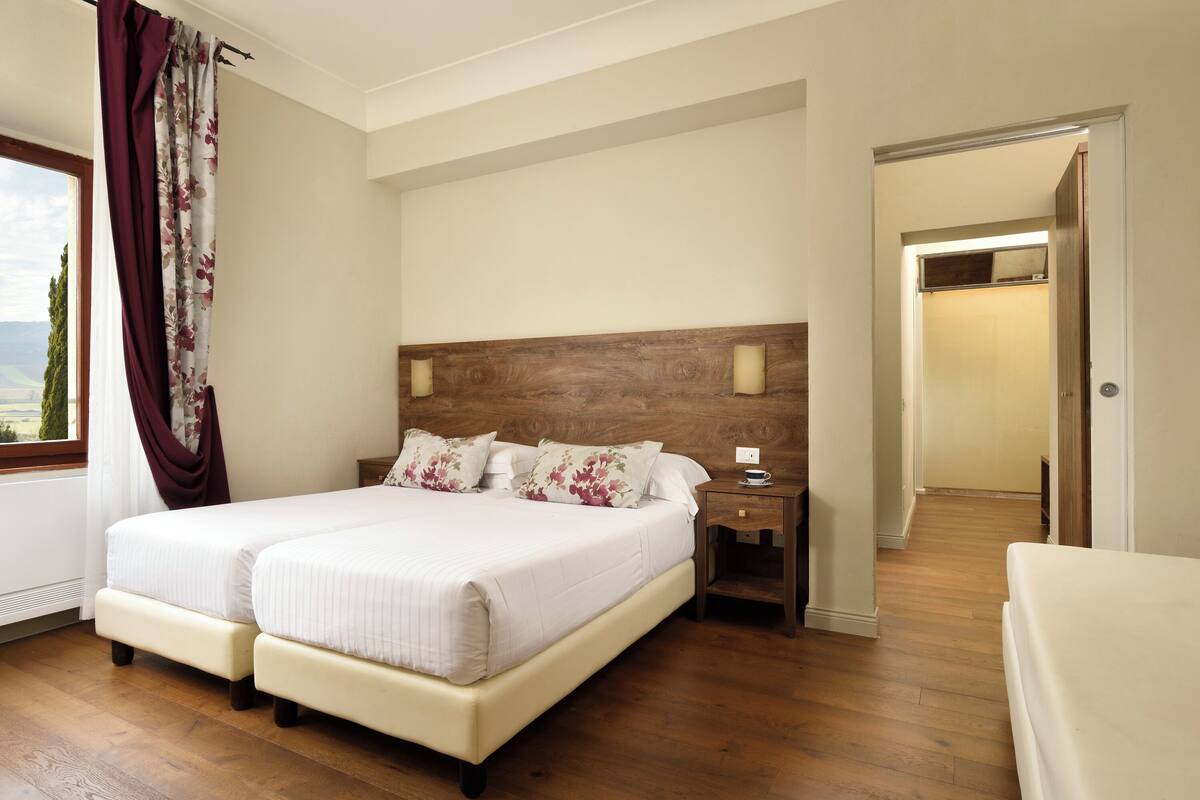 A double bed with a wooden headboard, a bedside table, and a nightstand.