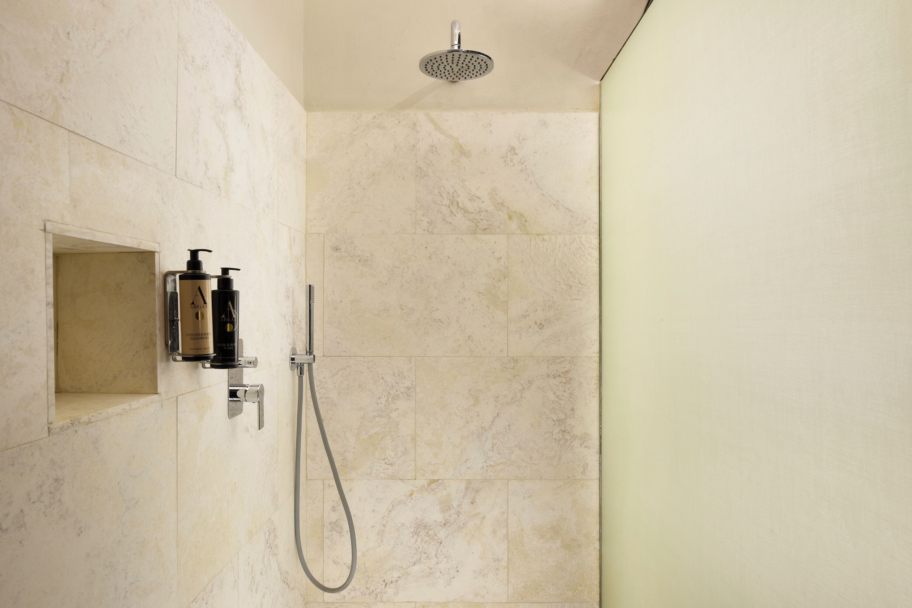 Ducha con cabezal de mano y panel de control en la pared.
