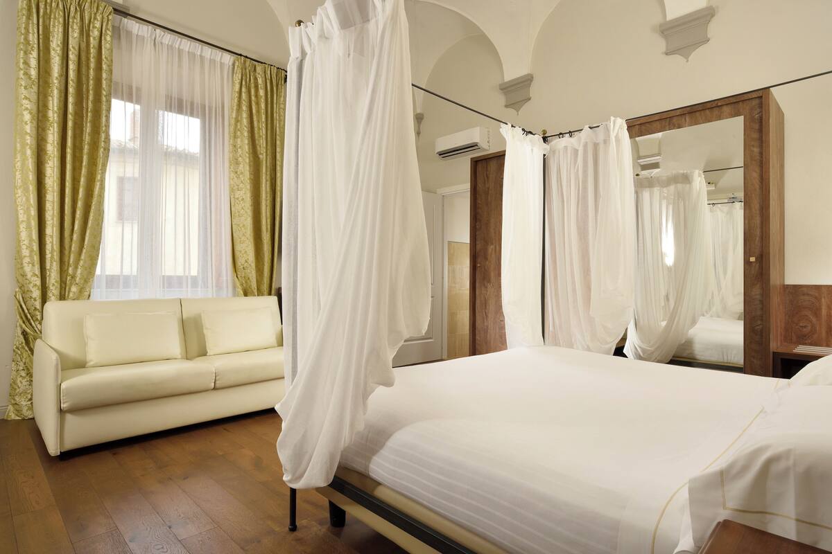 A bedroom with a bed, a sofa, and a large mirror.