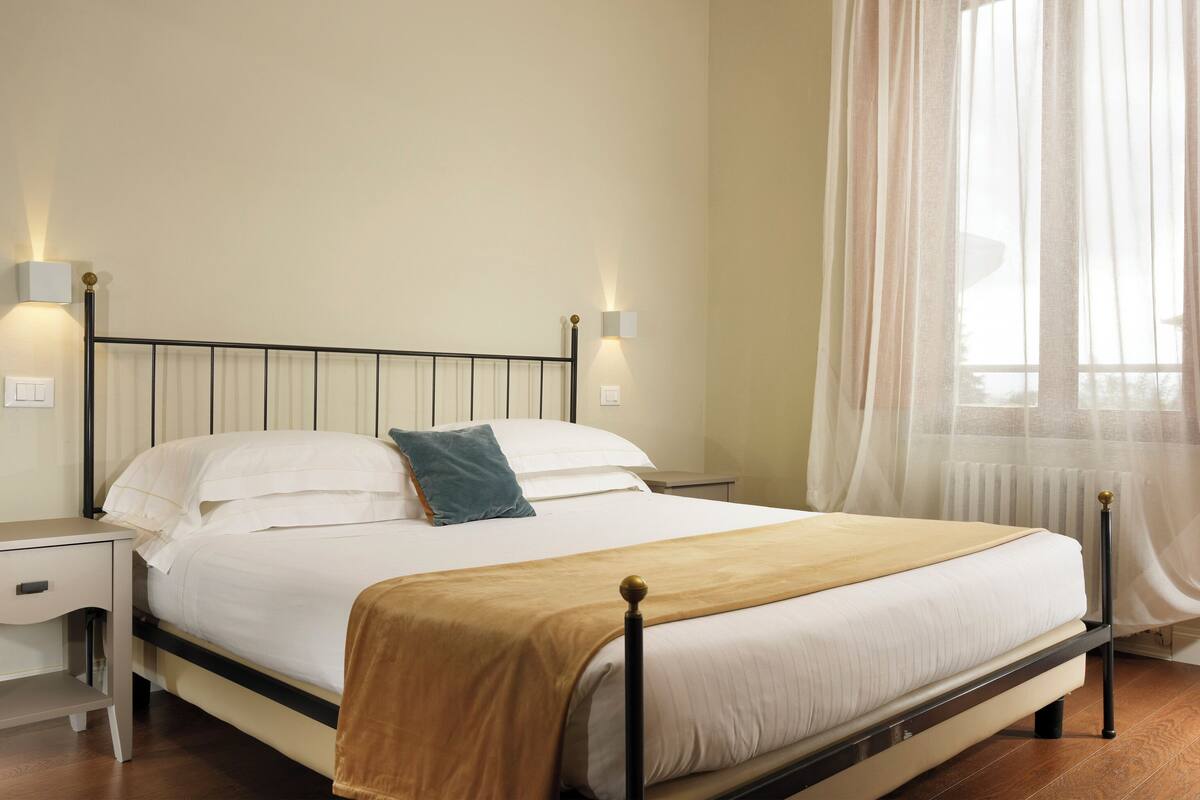 A neatly made bed with a headboard, a bedside table, and a lamp on each side.