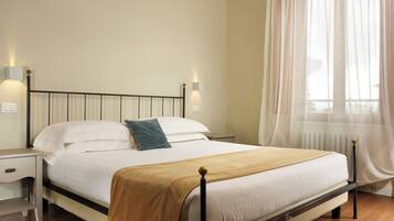 A neatly made bed with a headboard, a bedside table, and a lamp on each side.