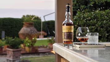 Uma garrafa de rum Plantation Original Dark, um copo de rum e um copo de água sobre um tabuleiro.