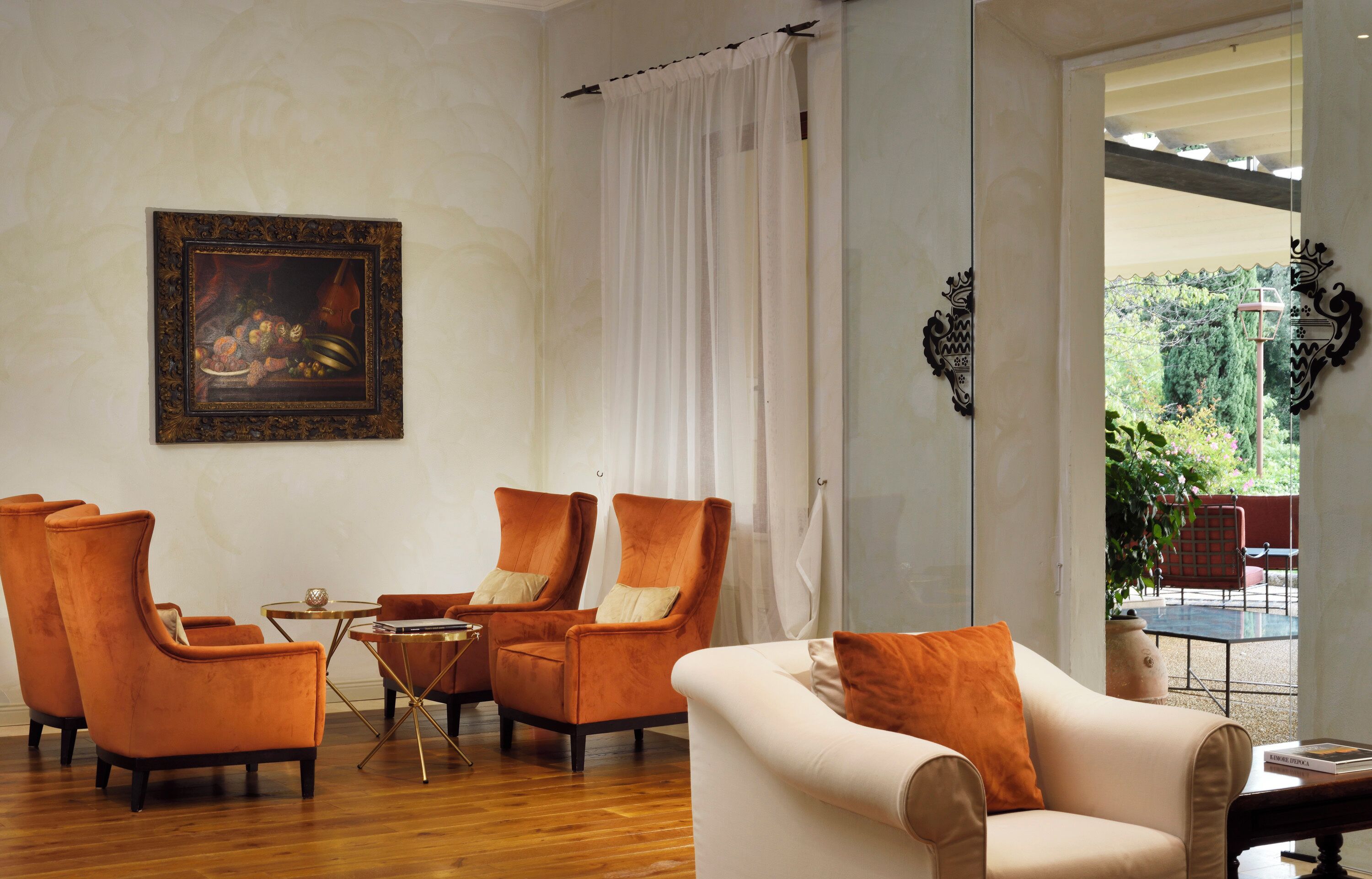 Un salón con chimenea, dos sillones naranja, un sofá blanco y una mesita.