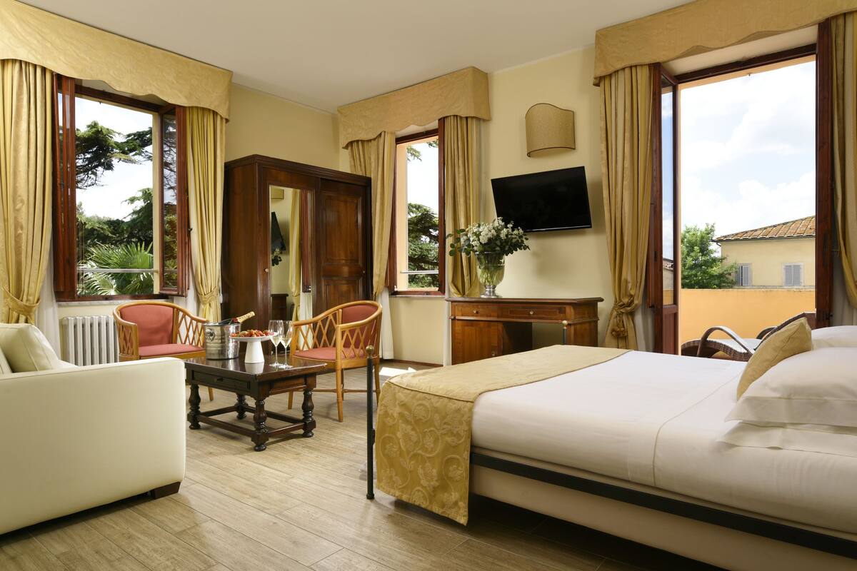 A hotel room with a bed, a desk, a chair, a television, and large windows.