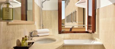 A modern bathroom with a beige marble sink, a bathtub, and a large mirror.