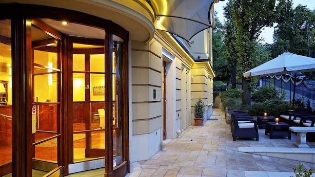 L’entrée de l’hôtel est dotée d’une porte en verre, et il y a un espace extérieur aménagé avec des tables et des chaises, ainsi qu’une terrasse couverte.