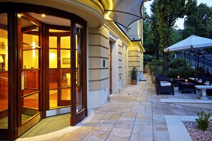 L’entrée de l’hôtel est dotée d’une porte en verre, et il y a un espace extérieur aménagé avec des tables et des chaises, ainsi qu’une terrasse couverte.