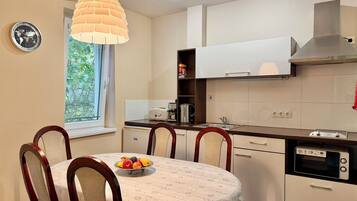 A modern kitchen with white cabinets, a built-in oven, and a dining area with a round table and chairs.