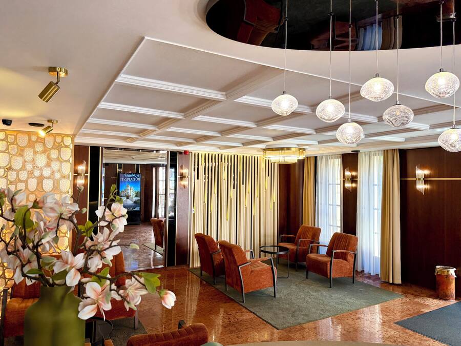 Un vestíbulo de hotel con un diseño moderno, que incluye una zona de estar con sillas y un jarrón de flores.